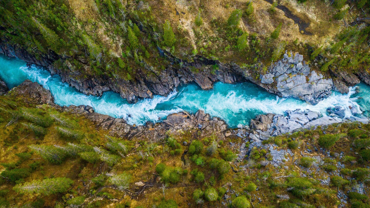 An aerial view of a vibrant blue river flowing between cliffs.