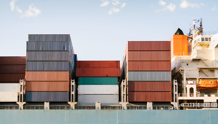 Shipping containers are shown neatly stacked on a ship deck. 