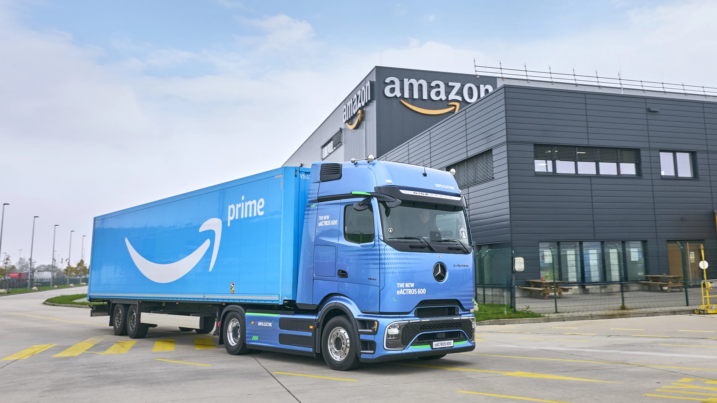 A blue truck parked outside an Amazon facility.