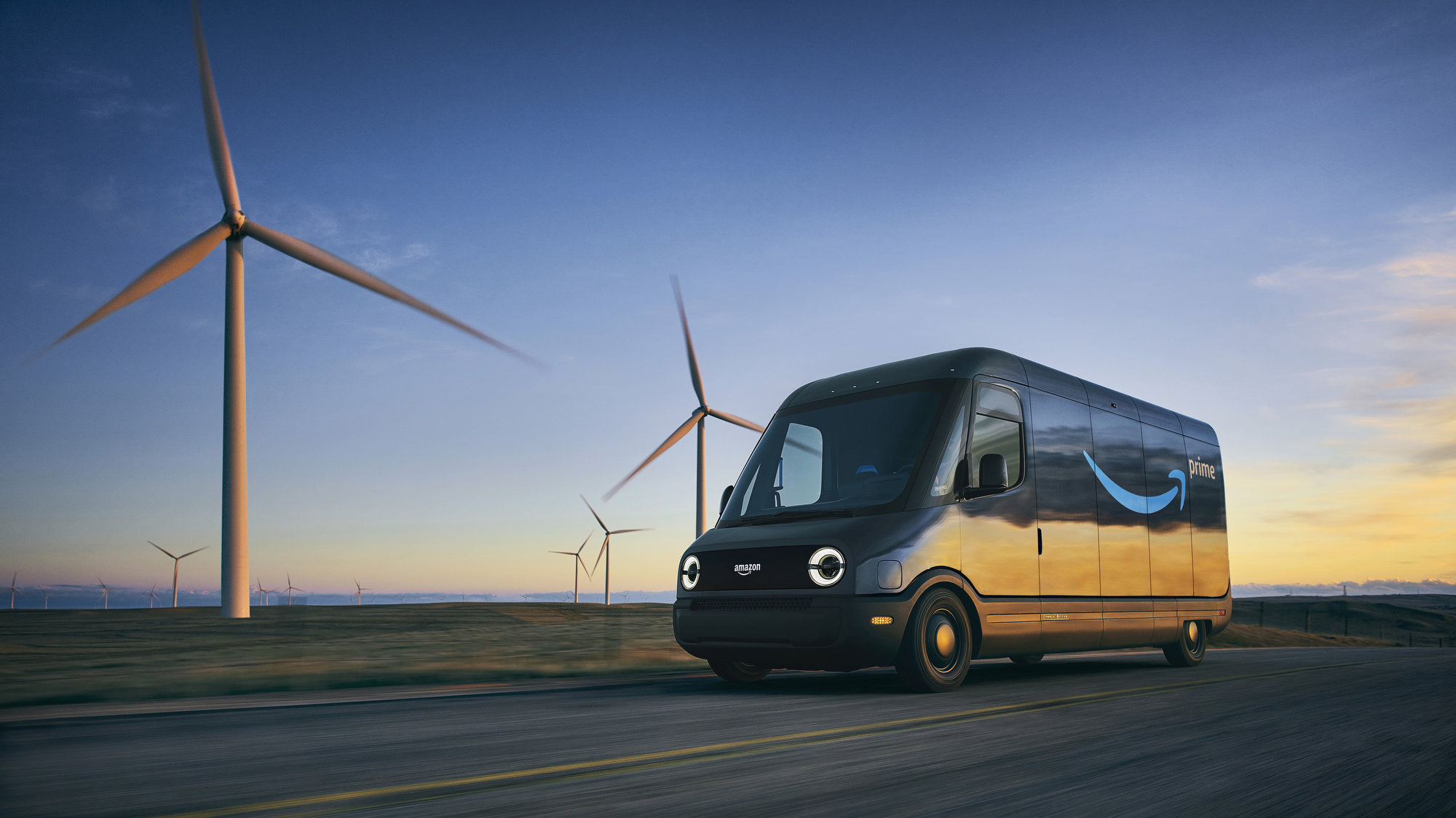 An Amazon Rivian van drives past wind turbines on a road.