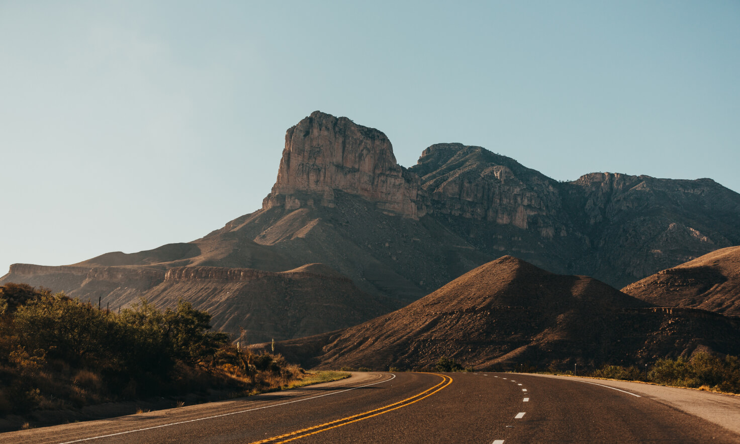 A desert landscape is shown in the distance in front of an open road.