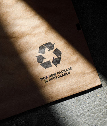 Sun shines over a portion of an Amazon paper padded mailer with a recycling icon and text that says: This new package is recyclable.