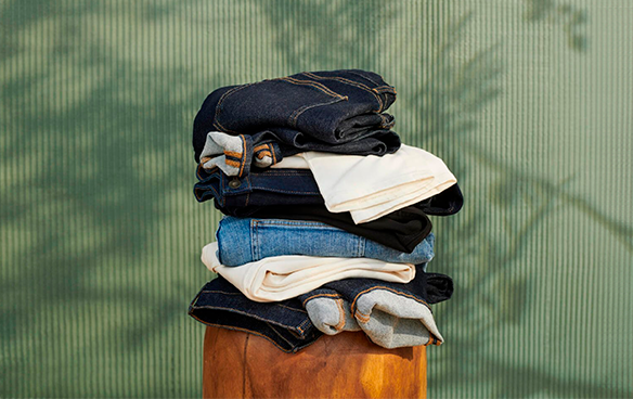 A stack of folded clothes is shown on a stool.