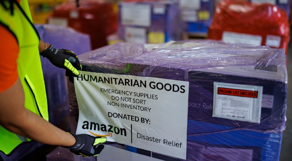 A person wearing a yellow safety vest prepares a pallet of emergency supplies. 