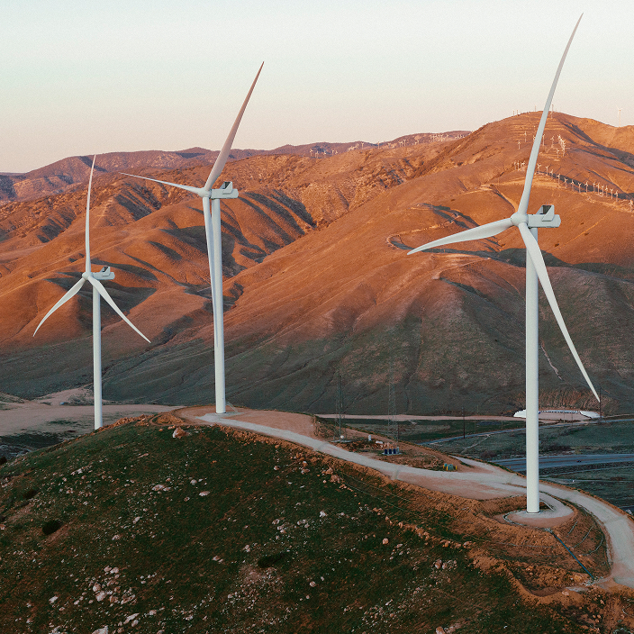 Three wind turbines at dusk in a mountainous, desert climate. 