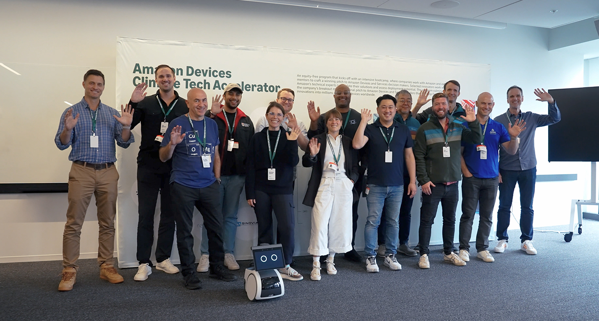 A group of people people stand in front of a white board in an office space. 