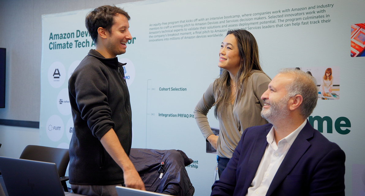 Three people stand smiling in an office space. 