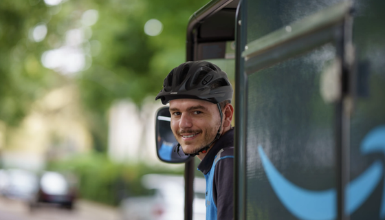 A person wearing a helmet smiles from the window of a vehicle. 