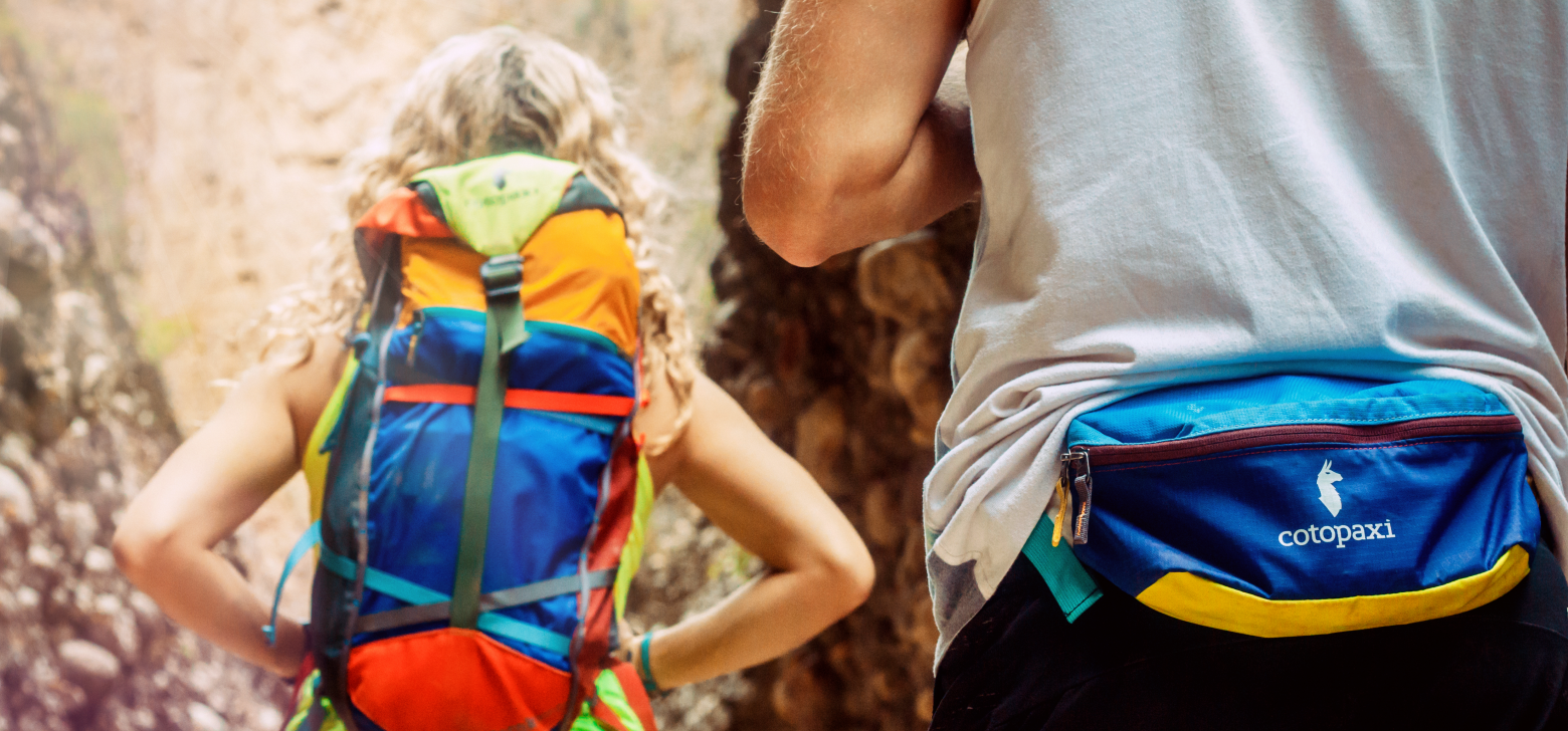 Two people are shown hiking with backpacks. 