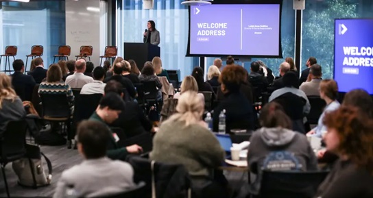A person speaking from a podium to a crowd of people. 