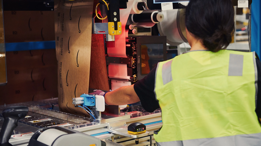 A person loads a roll of paper into packaging machinery. 