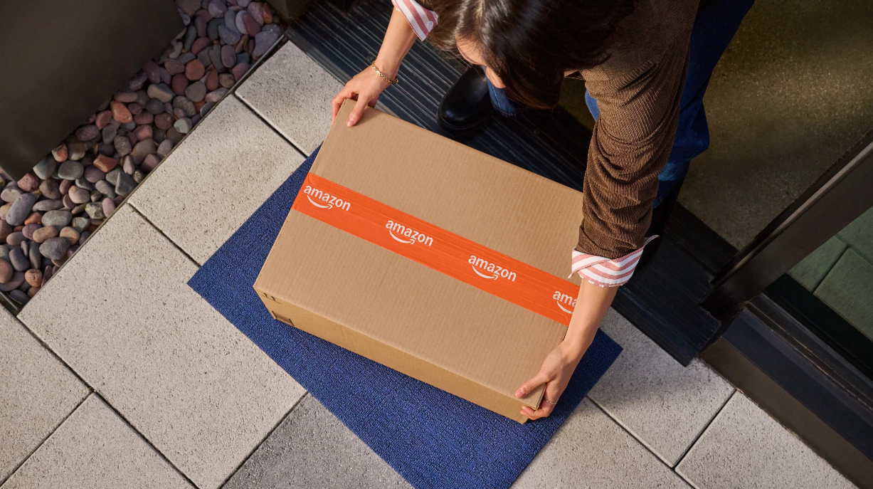 A person picks up a cardboard box from the ground. 