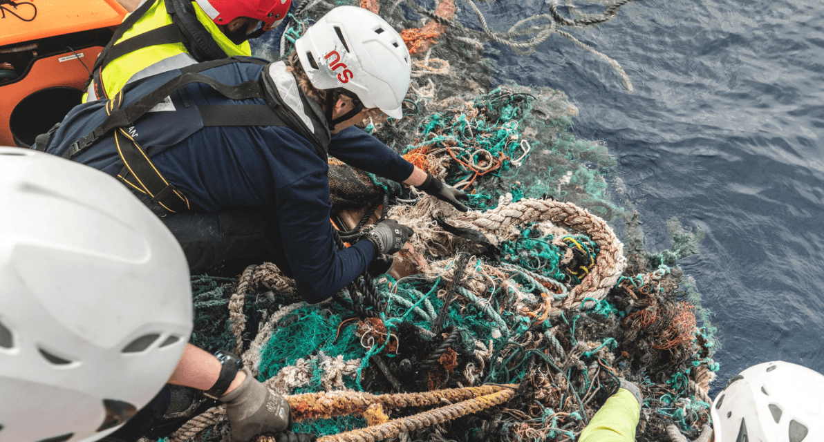 People in hard hats work together to remove trash from the ocean. 