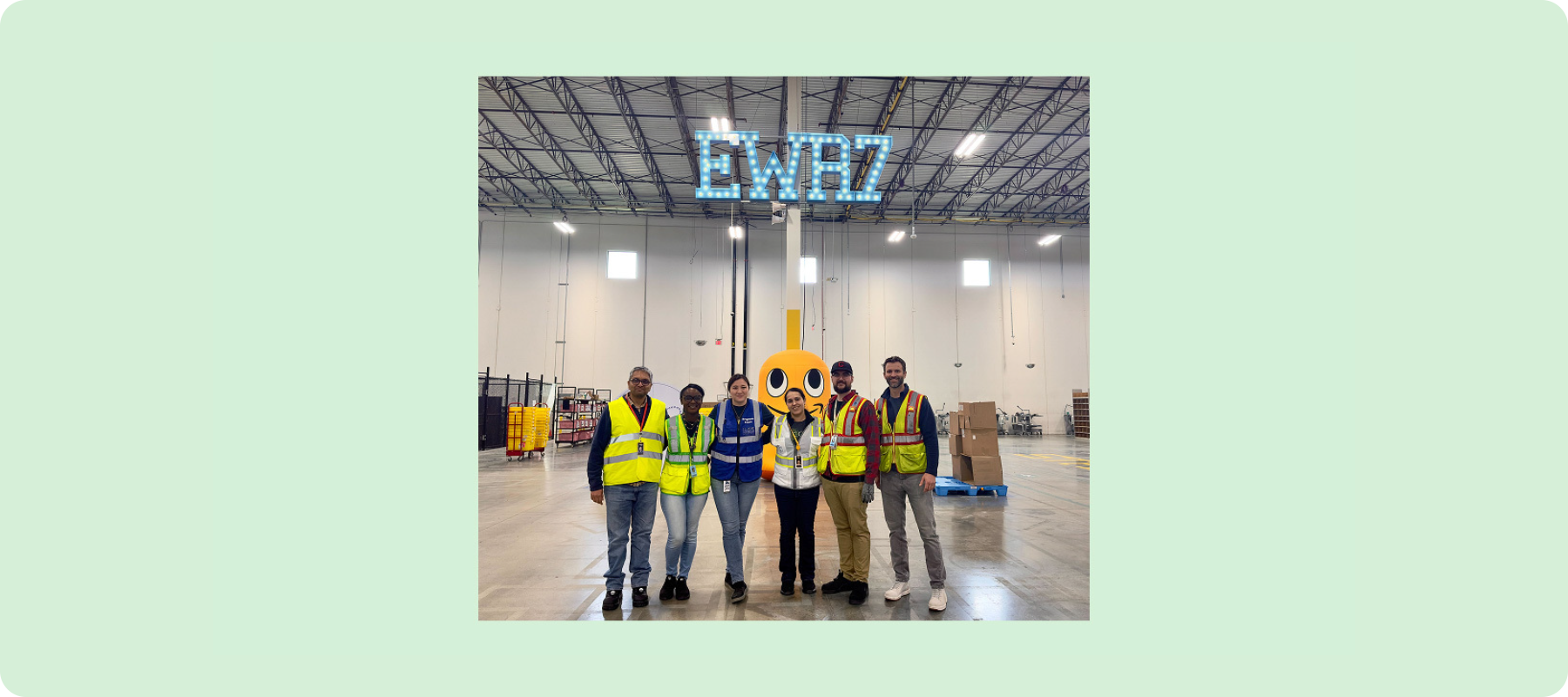 A group of people stand smiling wearing yellow safety vests.