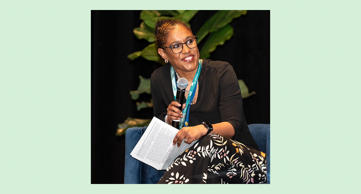 A person speaks into a microphone while sitting. 
